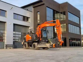 Koparka Hitachi w trakcie wyburzania budynku